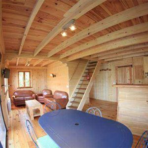 Intérieur chaleureux dun chalet en bois, avec salon et cuisine ouverte.