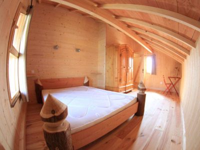 Chalet en bois chaleureux avec un lit douillet et des poutres apparentes.