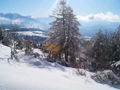 Cabane perchée en bois, entourée de neige et de montagnes en Provence-Alpes-Côte dAzur.
