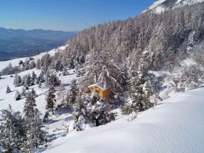 Cabane en bois nichée dans la neige, entourée de sapins en Provence-Alpes-Côte dAzur.