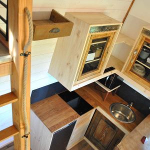 Cabane en bois avec cuisine moderne et mezzanine, ambiance chaleureuse et cosy.