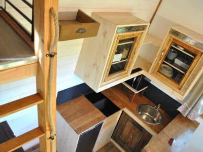 Cabane en bois avec cuisine moderne et mezzanine, ambiance chaleureuse et cosy.