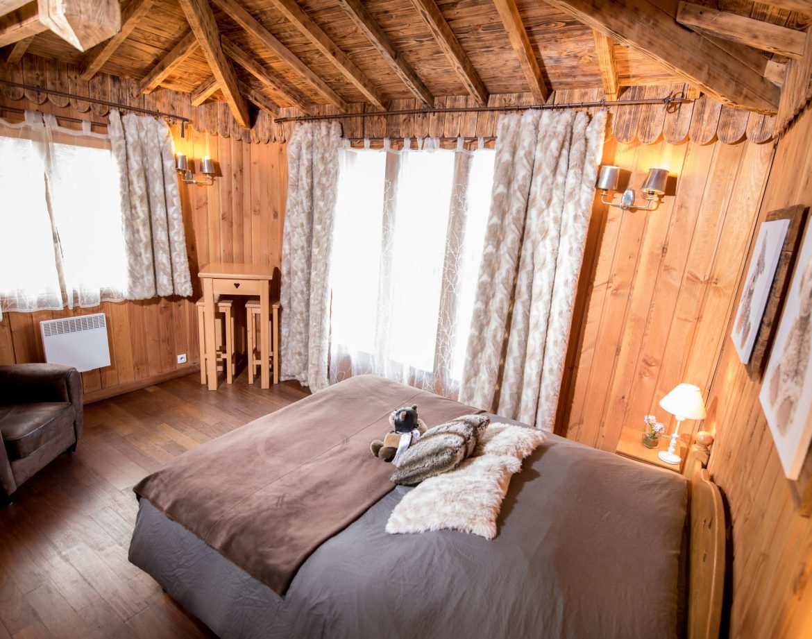 Chalet en bois chaleureux avec lit douillet et lumière naturelle abondante.