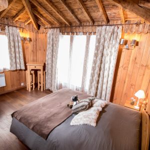 Chalet en bois chaleureux avec lit douillet et lumière naturelle abondante.