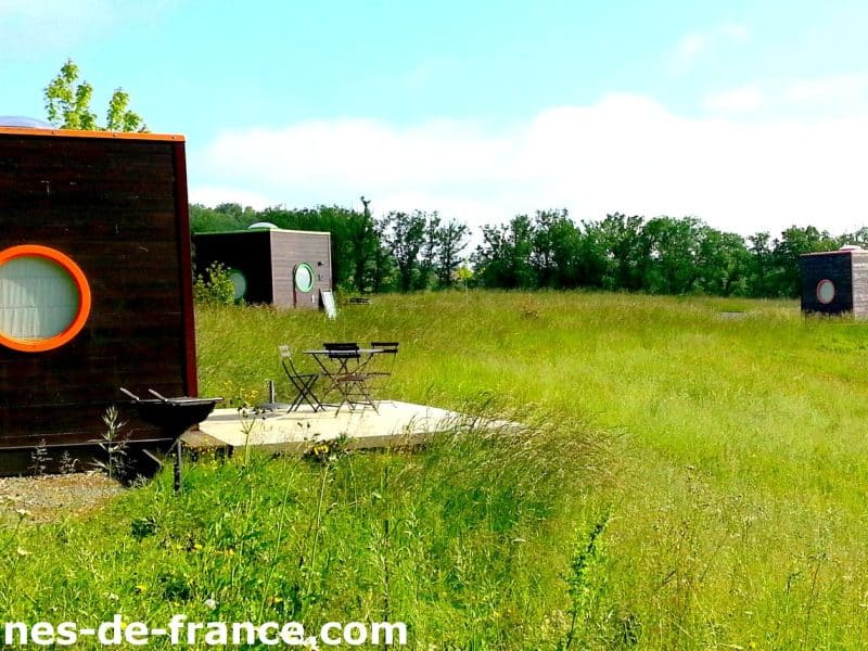 Cabanes modernes en pleine nature, entourées de verdure et avec terrasses privées.