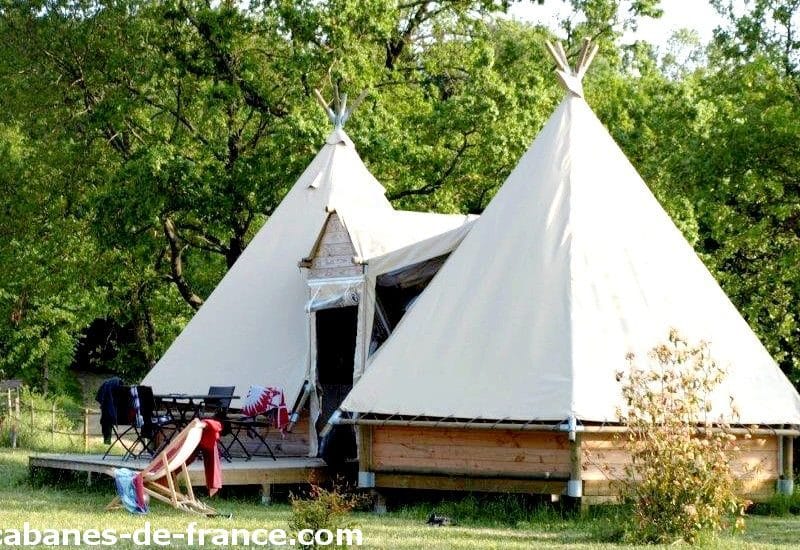 Tentes tipis spacieuses en pleine nature, avec terrasse et mobilier extérieur.