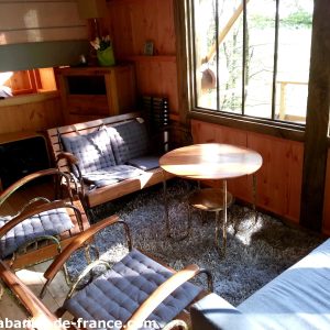 Cabane en bois avec un salon lumineux et des fauteuils confortables.