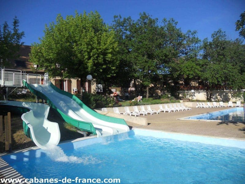 Cabanes de France avec piscine et toboggan, entourées de verdure.