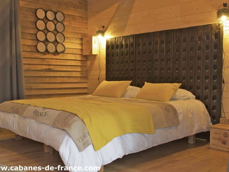 Chalet en bois avec un lit douillet et des murs en panneaux de bois chaleureux.