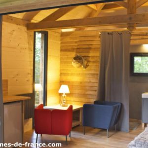 Cabane en bois avec un coin salon cosy et une lumière chaleureuse.