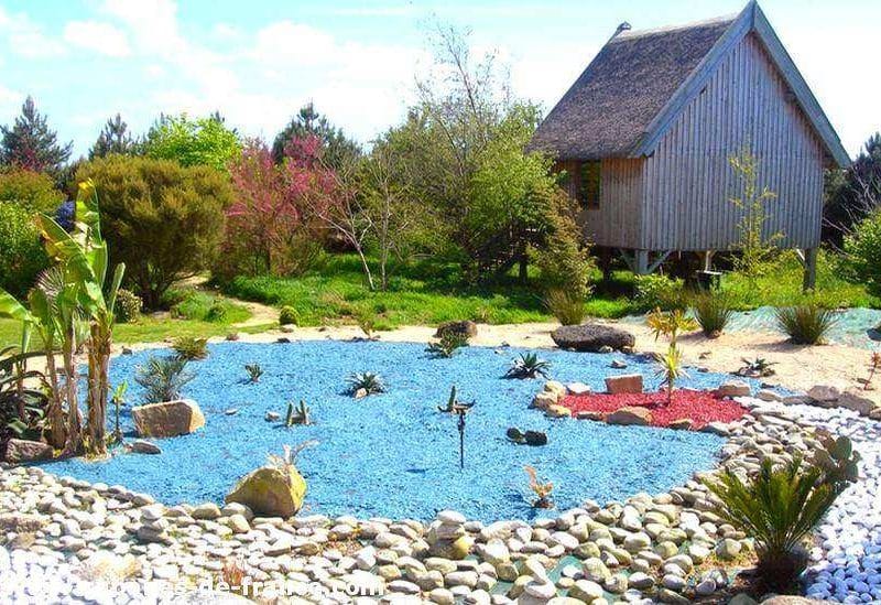 Chalet en bois entouré dun jardin coloré avec des pierres et des plantes exotiques.