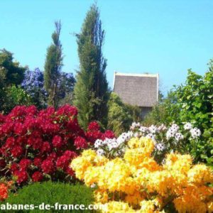 Cabanes de France entourées de fleurs colorées et verdure luxuriante.