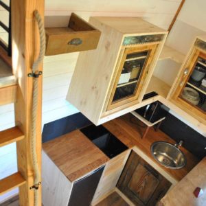 Cabane en bois avec cuisine équipée et mezzanine lumineuse.
