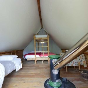 Tente lodge cosy en Auvergne, avec un poêle à bois et des lits confortables.