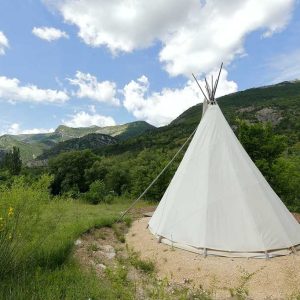 Tipi en pleine nature, entouré de montagnes verdoyantes en Auvergne-Rhône-Alpes.