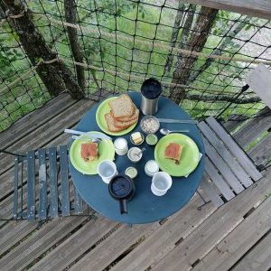 Table en bois avec petit-déjeuner dans une cabane perchée en Auvergne-Rhône-Alpes.