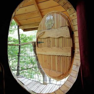 Cabane perchée en Auvergne-Rhône-Alpes, avec une porte ronde en bois et vue sur la nature.