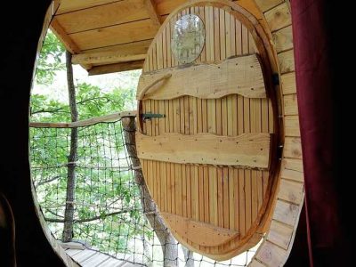 Cabane perchée en Auvergne-Rhône-Alpes, avec une porte ronde en bois et vue sur la nature.