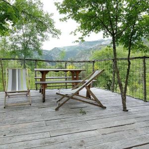 Terrasse en bois dun hébergement insolite avec vue sur les montagnes verdoyantes.