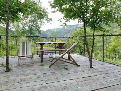 Terrasse en bois dun hébergement insolite avec vue sur les montagnes verdoyantes.