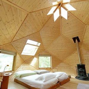Hébergement insolite en forme de dôme, intérieur en bois avec lumière naturelle.
