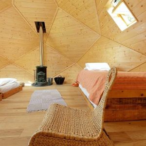 Dôme en bois avec lit confortable et poêle à bois, idéal pour un séjour insolite.