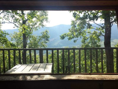 Cabane perchée en bois avec vue panoramique sur les montagnes verdoyantes.