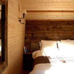 Chalet en bois chaleureux avec lit douillet et murs en bois naturel.