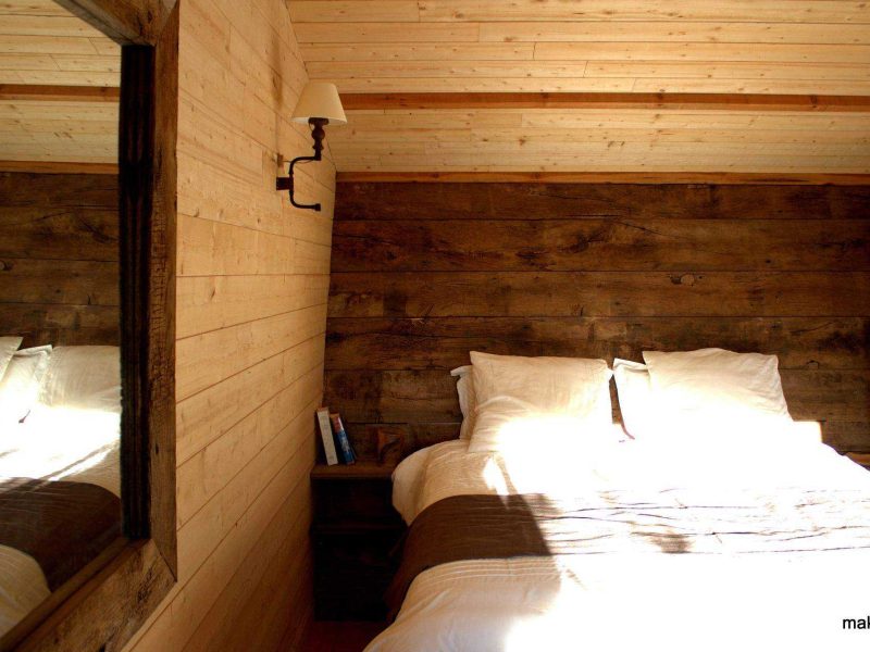 Chalet en bois chaleureux avec lit douillet et murs en bois naturel.