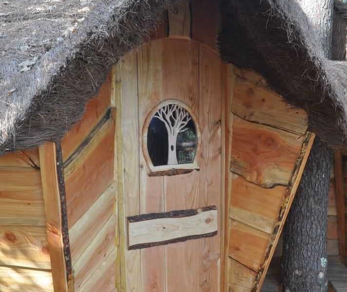 Cabane en bois avec un toit de chaume et une porte en bois sculptée.