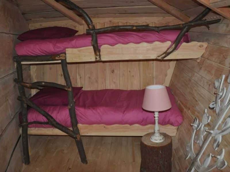 Chalet en bois avec lits superposés et décoration rustique, ambiance chaleureuse.