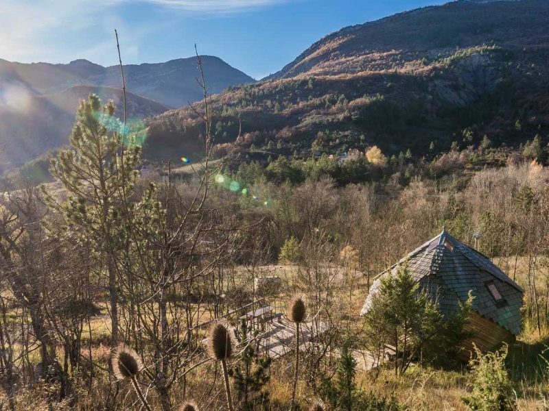 Cabane en bois atypique, nichée dans la nature avec vue sur les montagnes.