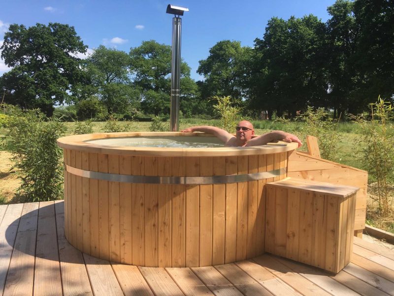 Hébergement en pleine nature avec un jacuzzi en bois, idéal pour se détendre.