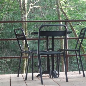 Table et chaises en bois sur une terrasse, entourée de verdure en Aquitaine.