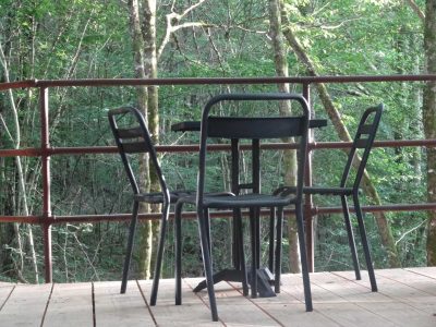 Table et chaises en bois sur une terrasse, entourée de verdure en Aquitaine.