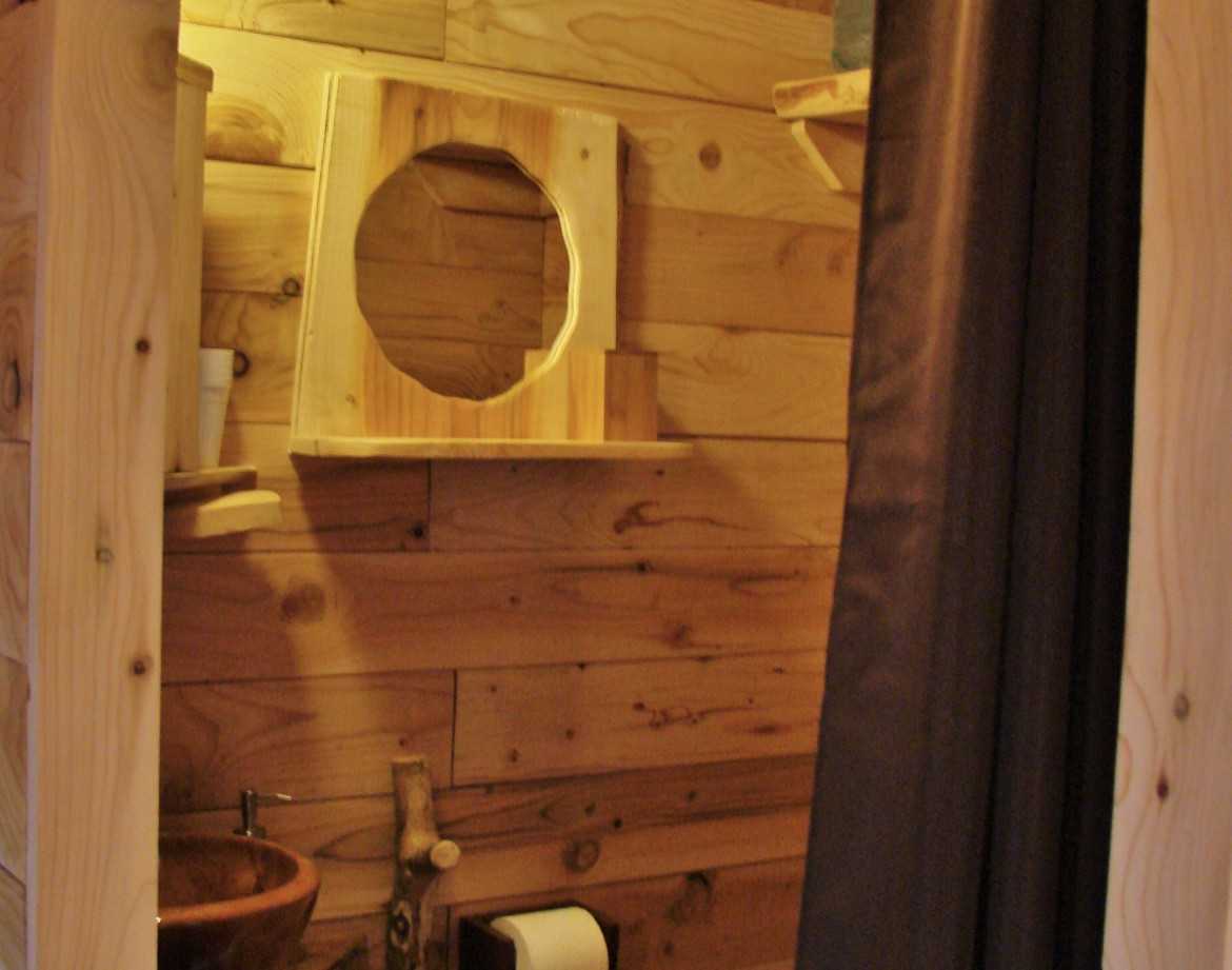 Cabane en bois avec un lavabo en pierre et des murs en bois naturel.