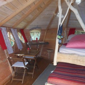 Cabane en bois avec lit douillet et fenêtres colorées, au cœur des Pays de la Loire.