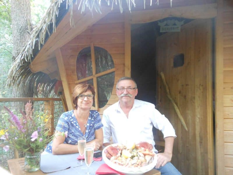 Cabane dans les arbres avec couple savourant un repas en plein air.