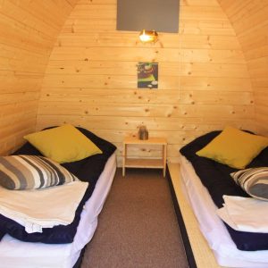 Hébergement insolite en forme de cabane en bois, avec lits jumeaux et décoration chaleureuse.