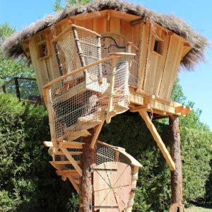 Cabane perchée en bois avec toit en chaume, entourée de verdure en Provence-Alpes-Côte dAzur.