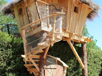 Cabane perchée en bois avec toit en chaume, entourée de verdure en Provence-Alpes-Côte dAzur.