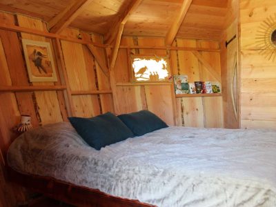 Cabane en bois chaleureuse avec un lit douillet et des murs en bois clair.