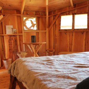 Cabane en bois cosy avec lit douillet et décor naturel en Provence-Alpes-Côte dAzur.