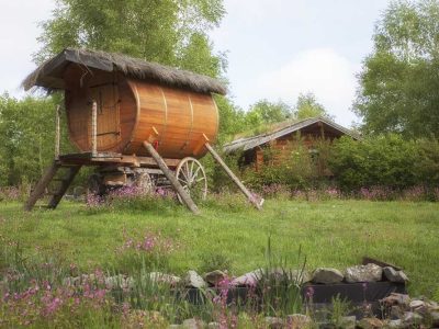 Hébergement insolite en Auvergne : roulotte en bois entourée de fleurs sauvages.