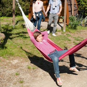 Hébergement insolite en cabane, avec un enfant se relaxant dans un hamac.