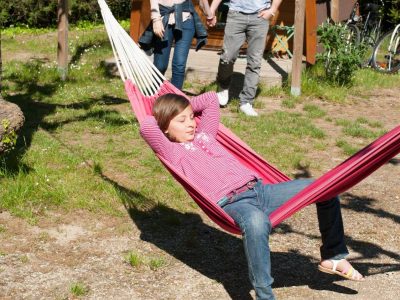 Hébergement insolite en cabane, avec un enfant se relaxant dans un hamac.