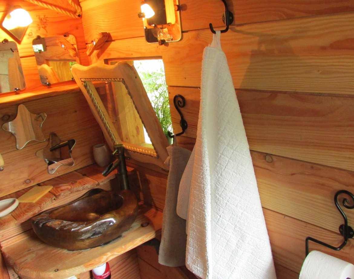 Intérieur dun hébergement insolite en Bretagne, avec un lavabo en bois et des murs en bois.