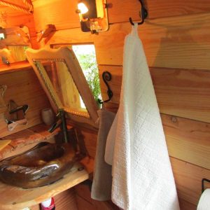 Intérieur dun hébergement insolite en Bretagne, avec un lavabo en bois et des murs en bois.