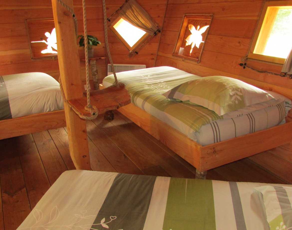 Chalet en bois avec lits confortables et fenêtres en forme de fleurs en Bretagne.