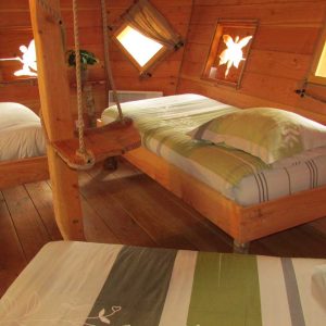 Chalet en bois avec lits confortables et fenêtres en forme de fleurs en Bretagne.